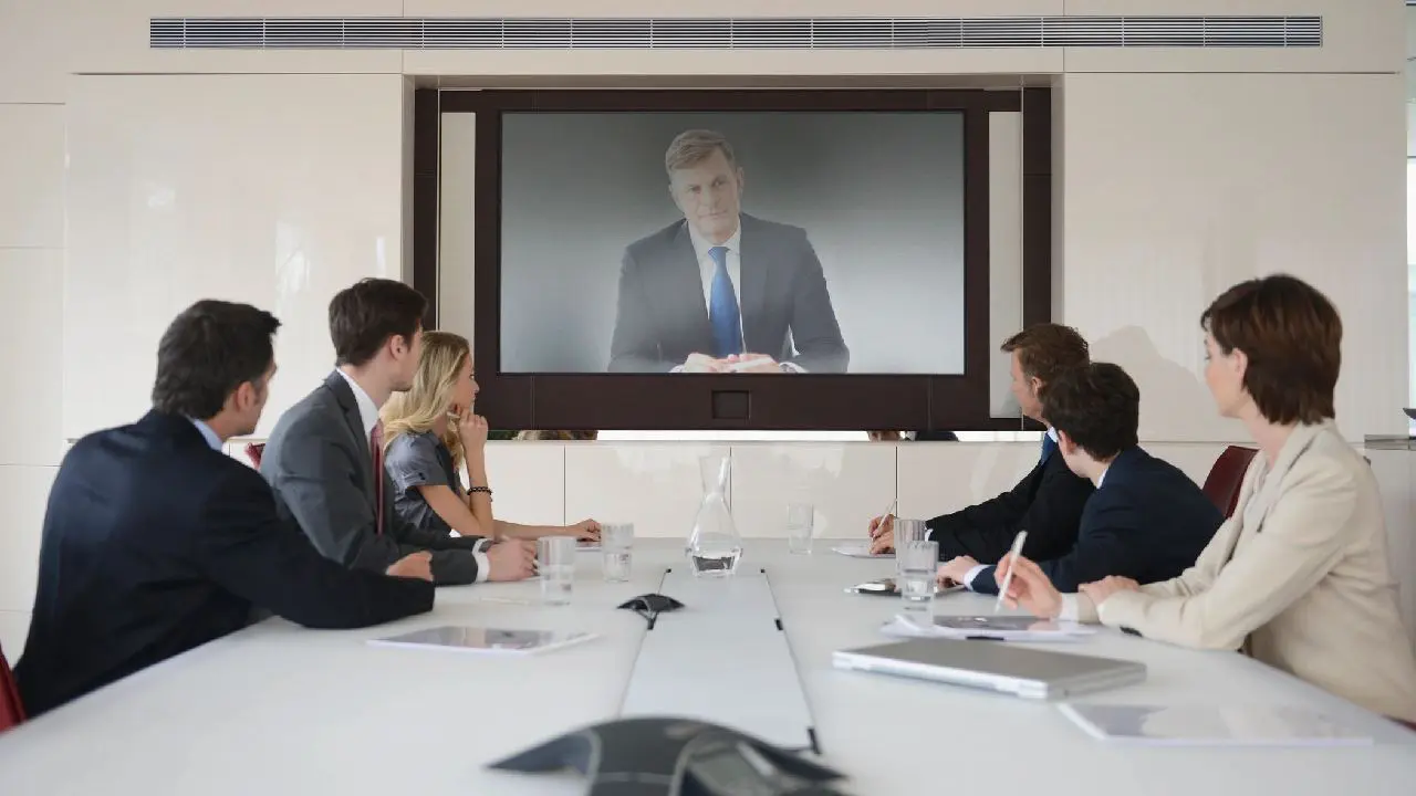 Professionals in a meeting room attentively watching a presentation on a screen.