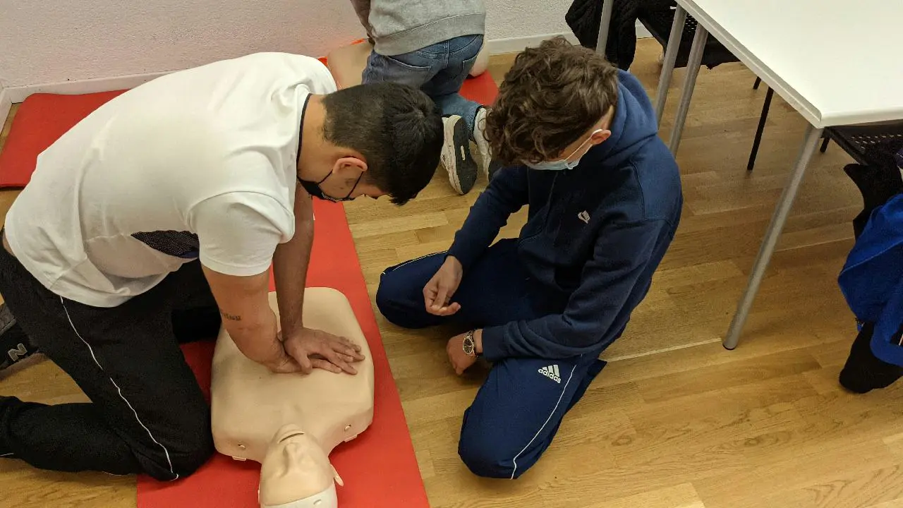 Two individuals practicing cpr on a medical training mannequin.