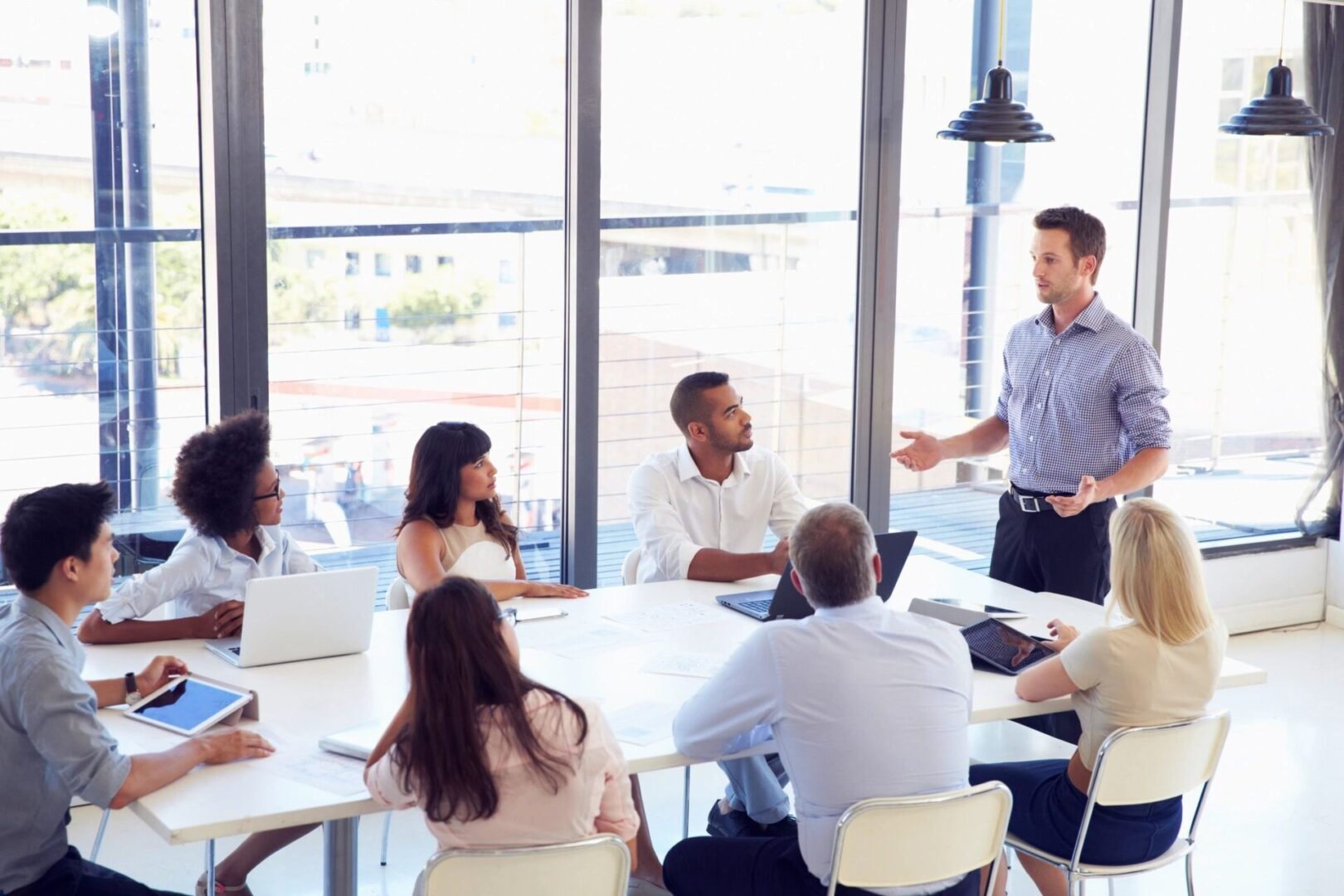 A group of professionals in a meeting with one person standing and presenting.