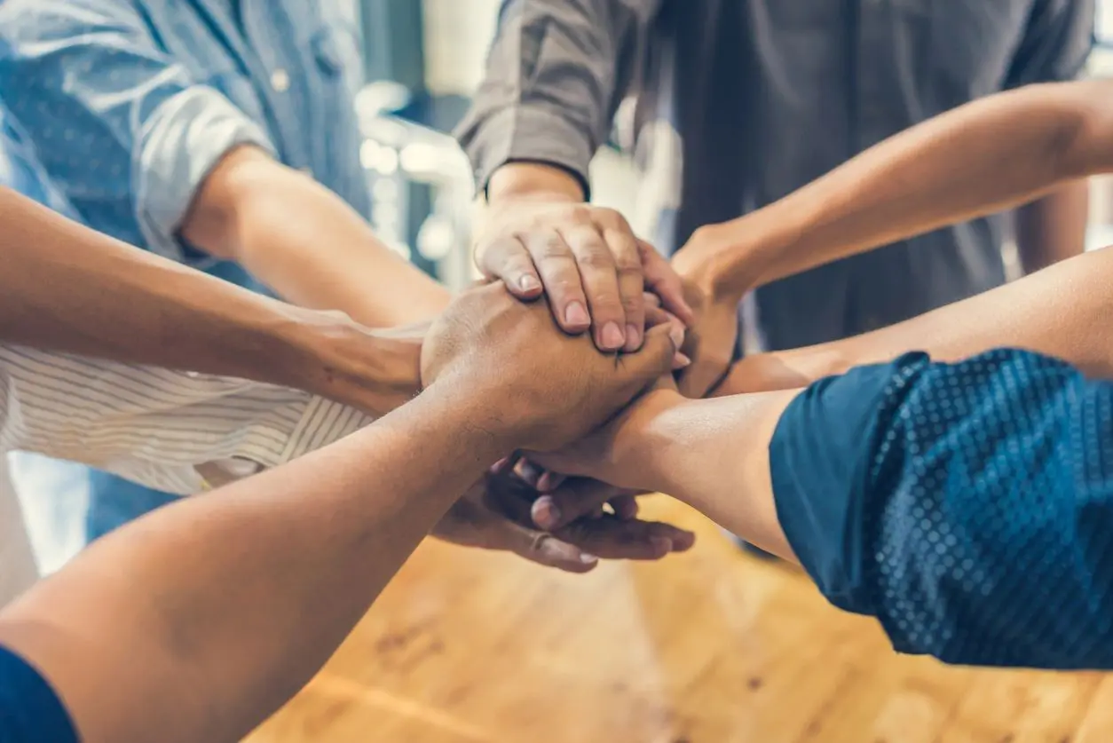 Team members stacking hands together in a show of unity and teamwork.