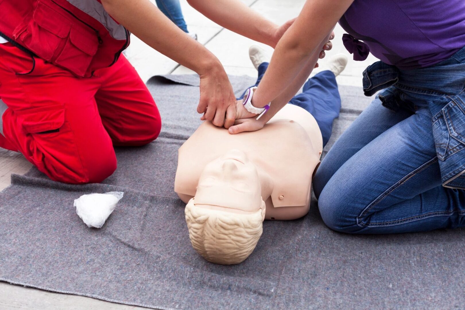 First aid training session with a person performing chest compressions on a cpr manikin.