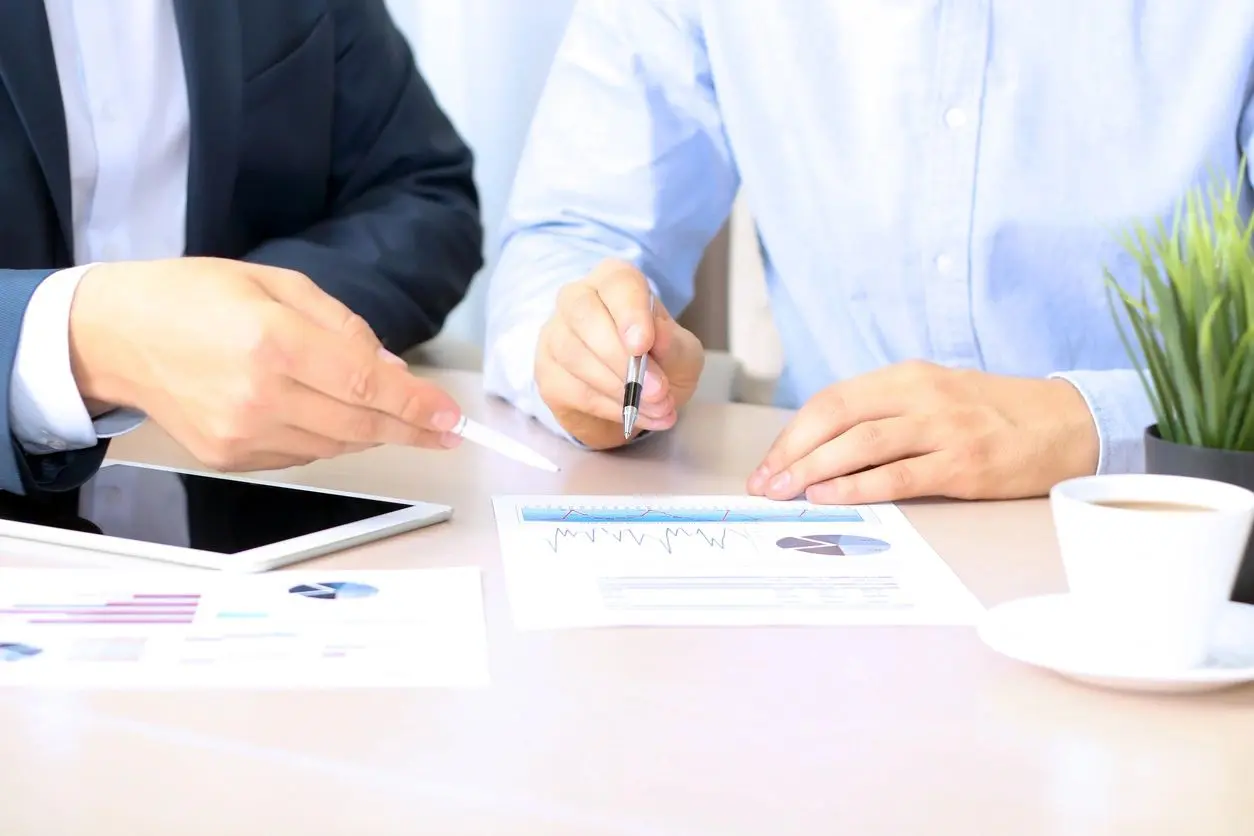 Two individuals reviewing graphs and charts at a business meeting.